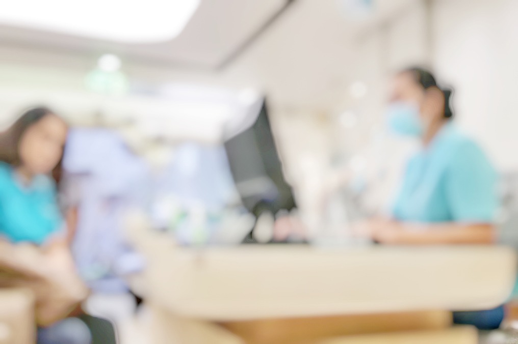 Blur abstract background of patients register at reception desk in hospital. Blurry nurse receptionists taking care new customers in medical clinic. Defocus reception area with worker. Healthcare concept.